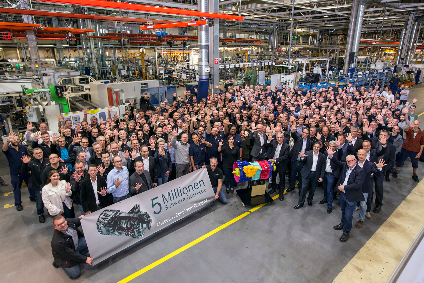 mid Groß-Gerau - Die stolze Mannschaft vor dem fünfmillionsten Getriebe, das anlässlich des Jubiläums bunt lackiert ist. Daimler